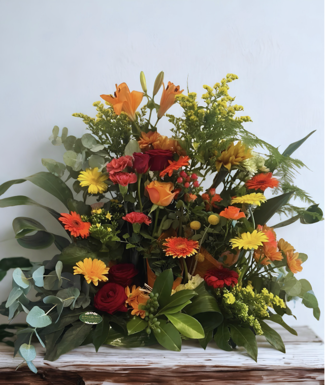 Grande composition florale orange, jaune et rouge avec feuillage